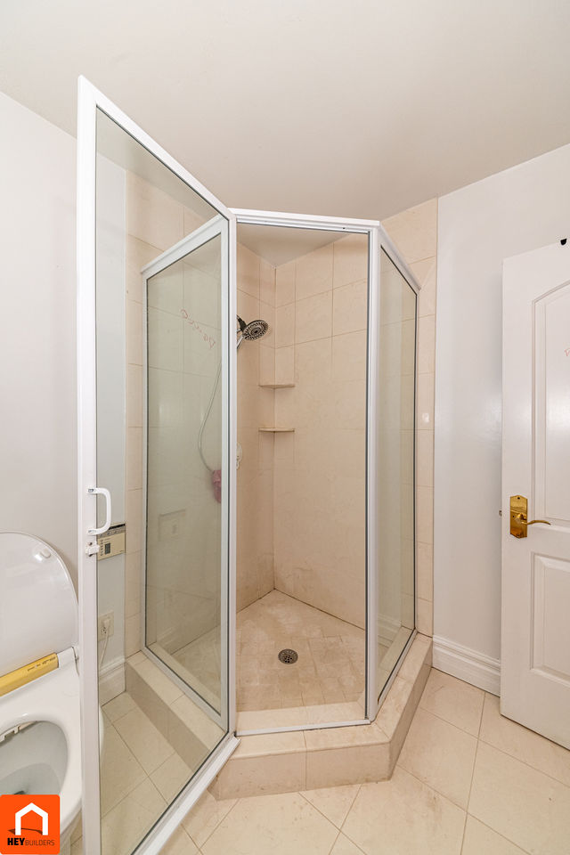 Master bathroom shower before renovation - dated tile and glass enclosure